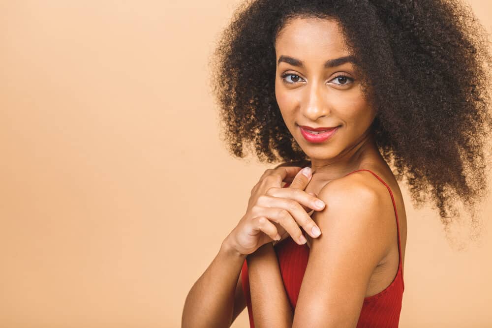 Black girl wearing a red shirt, bright red lipstick, and purple fingernail polish.