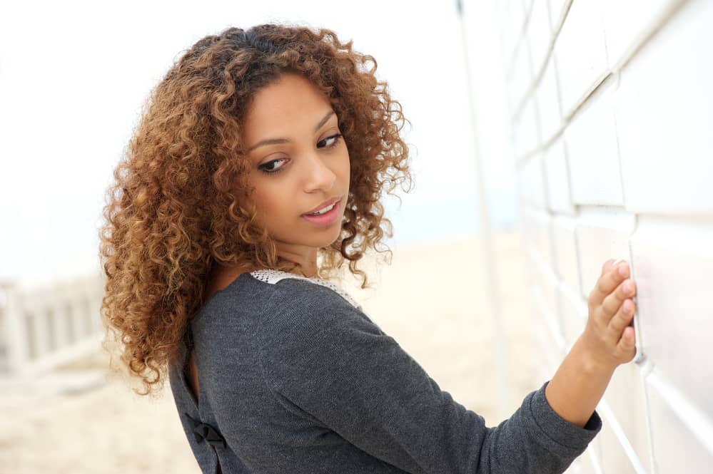 Female with the usual pre-lightening full balayage style on curly hair for a more noticeable lift.