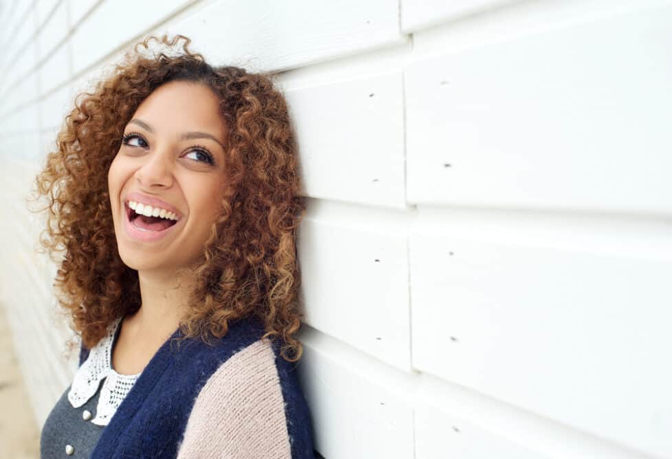 Lady laughing and enjoying life wearing curly short hair and partial highlights.