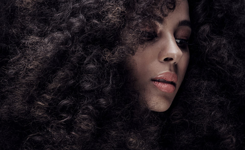 schattig zwart meisje dragen pre-gebonden hair extensions in een afro stijl gemengd met haar eigen haar.