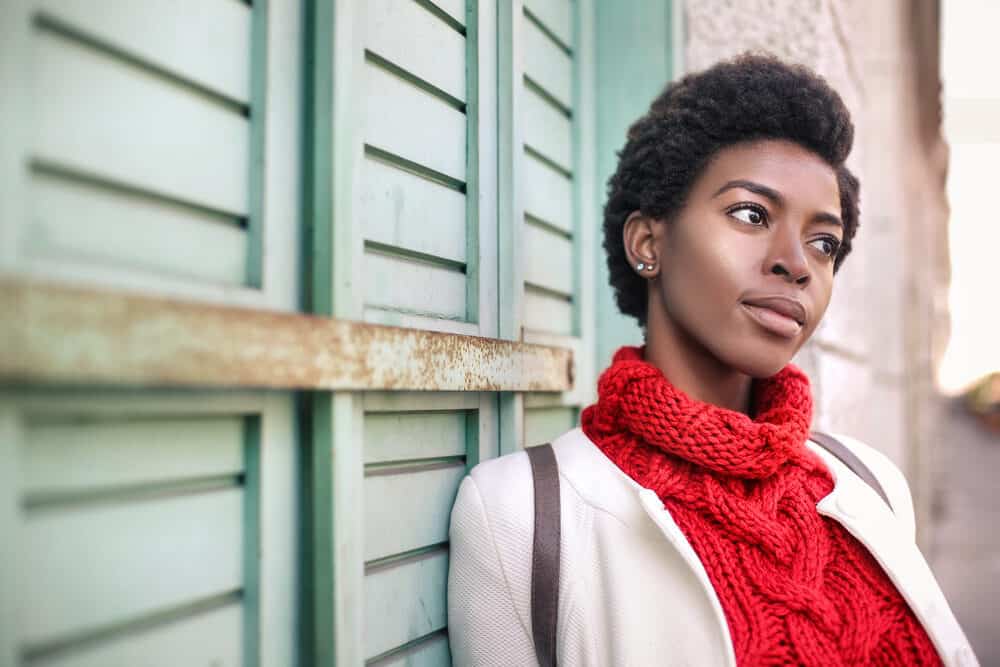 Female with a style that's off the hair type chart wearing a red sweater and white sports coat.