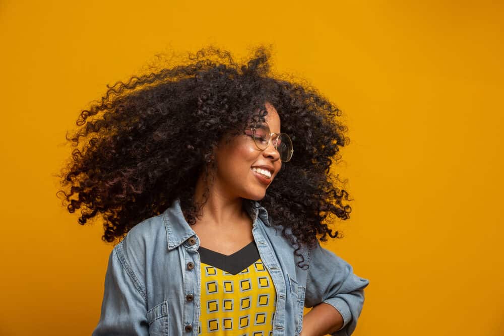 Cute black girl with curly hair wearing tape-in hair extensions on a minimum hair length