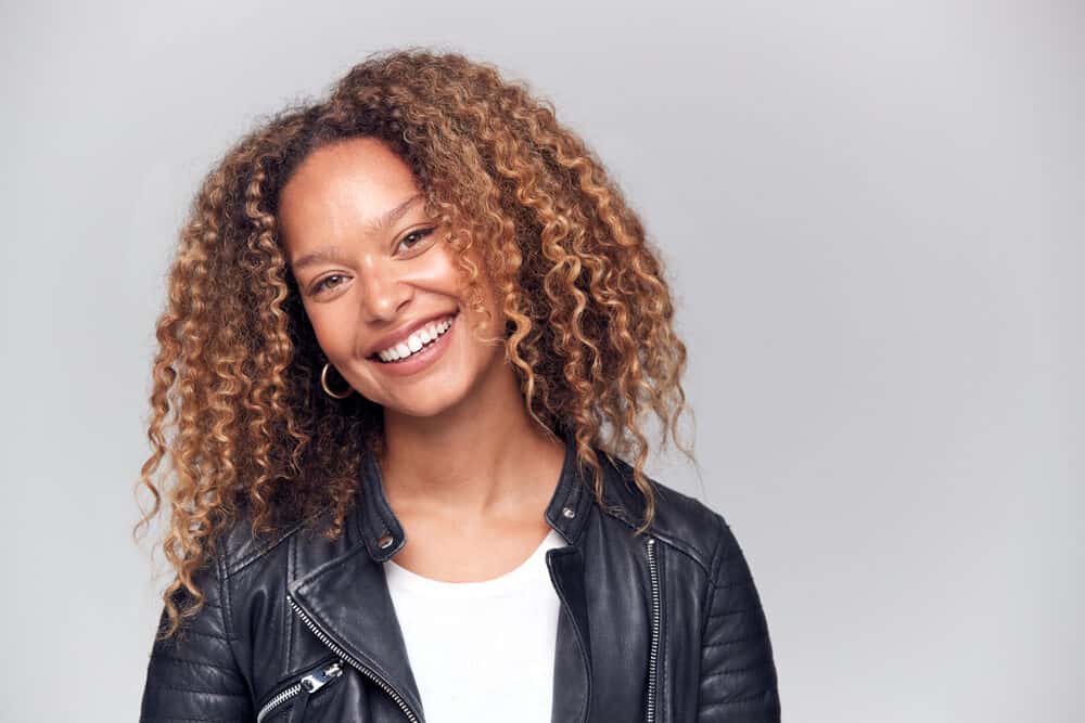 Black women with brown curly hair styled with light formula hairspray and hot rollers wearing a black leather jacket and a white t-shirt.