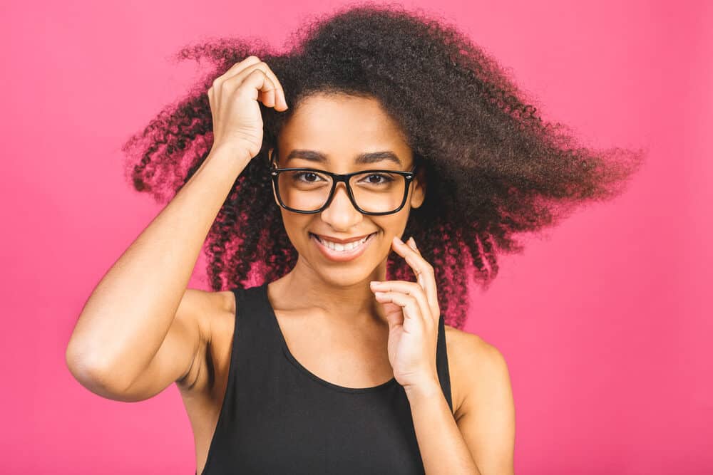 Female with curly type 3c natural hair wearing black glasses and black tank top.