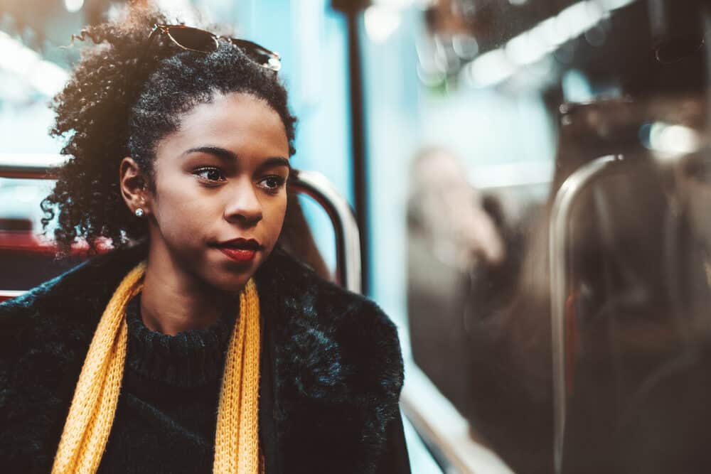 A serious black woman is wearing temporary hair extensions to increase the density of her fine thin hair extensions.