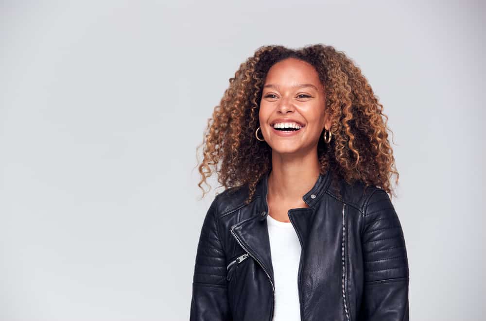 Pretty black girl with a nice smile wearing gold earrings, red lipstick, and a white t-shirt.