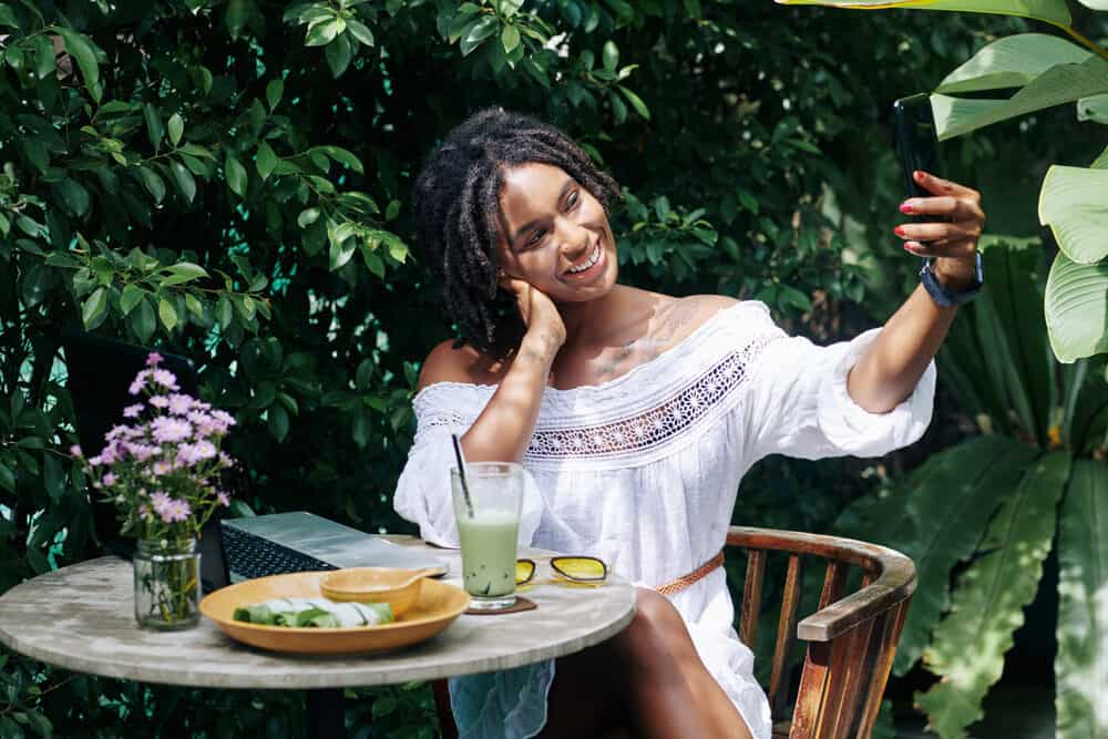 Black girl working on her laptop at an outdoor coffee shop.