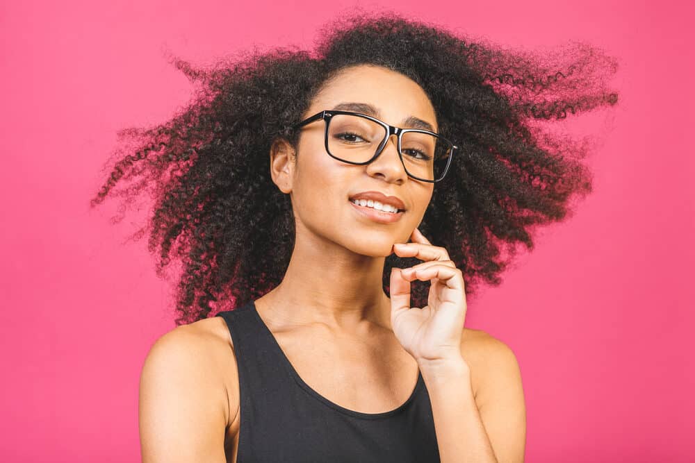 African American female rocking kinky curly i-tip extensions with red lipstick and a dark t-shirt.
