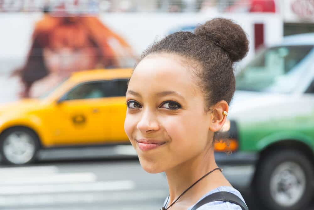 A black girl with dyed hair, blue eye shadow, and a great smile used a lice comb to treat lice instead of chemicals.