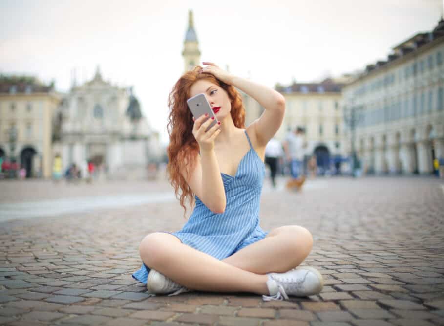 Beautiful female with a unique style sitting outside on the street taking a selfie while wearing alkaline perm.