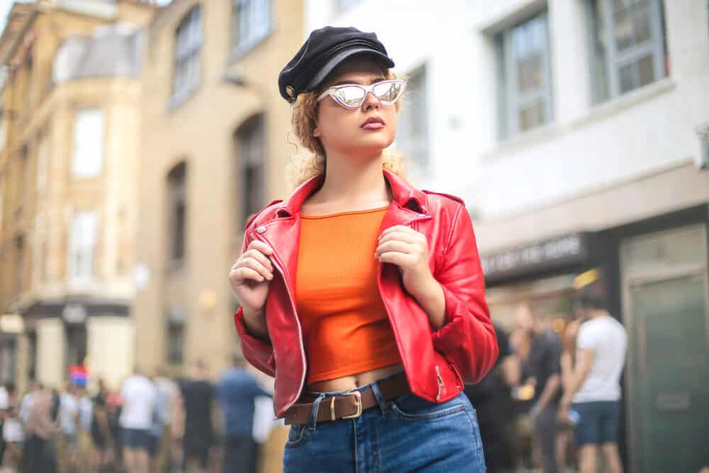 Stylish girl wearing a red leather jacket, blue jeans, and cool sunglasses with a type 2 wavy hair type