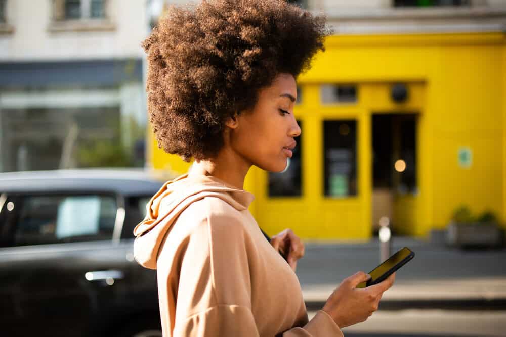 Lady with natural curls reading about her natural hair journey on the Curl Centric website.