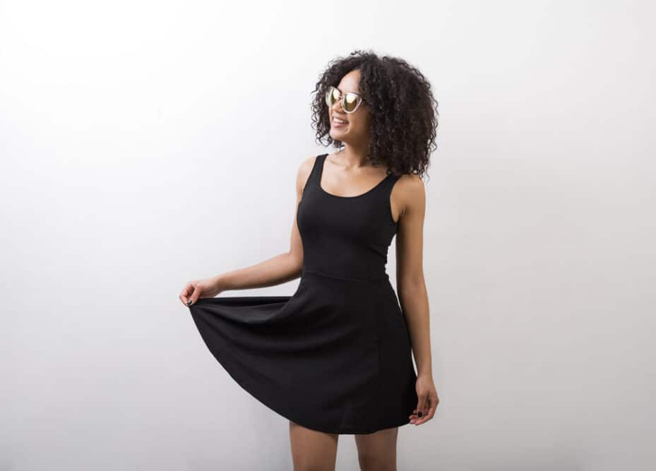 Lady wearing a black dress and sunglasses enjoying her curly hair journey with big curly waves