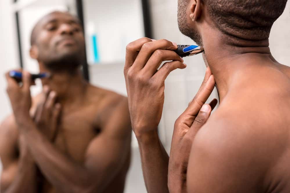 Black man trimming his own hair with a WAHL stainless steel lithium trimmer head.