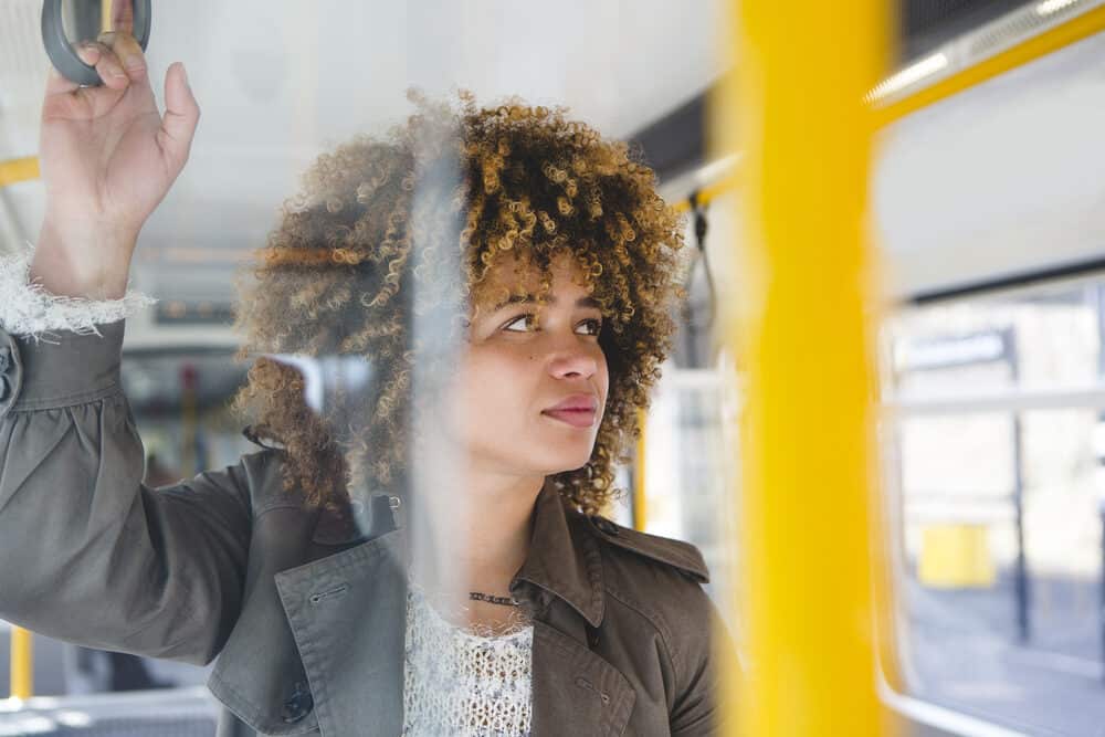 Black woman with curly tresses rushing downstairs with her phone in hand.