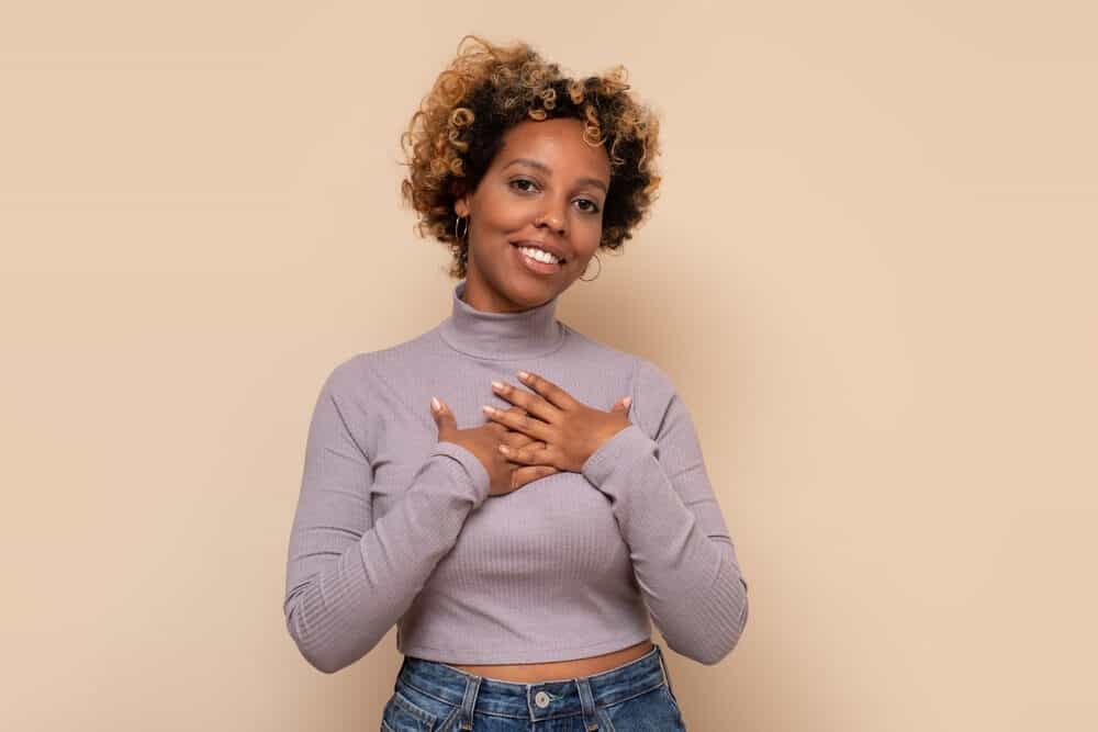 Black lady with curly hair that includes black, brown, orange, or yellow tones throughout