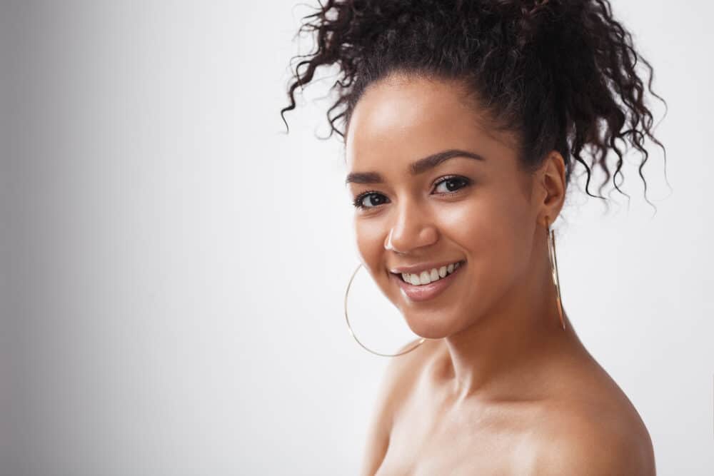 A light-skinned lady wearing neutral makeup preparing to start the curly hair method for wavy girls