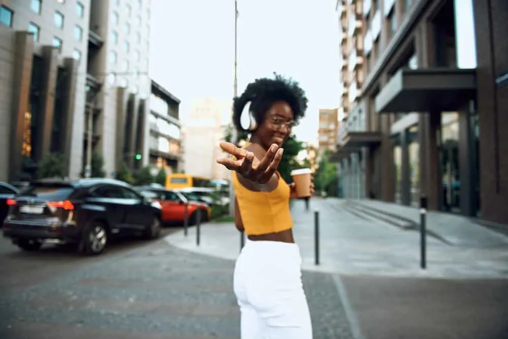 Best Blow Dryer for 4C Hair: Top Dryers for Women with Kinky Curly Natural Hair 17 Cute black girl with naturally wavy hair wearing a yellow shirt and white pants.