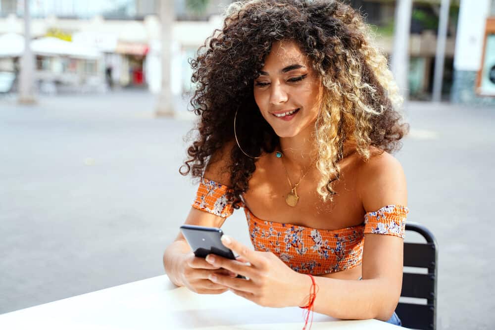 A Colombian woman researching how to maintain hair health and eliminate hair breakage using her iPhone.