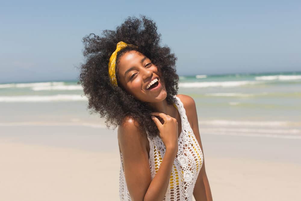 Black girl with curly hair and light caramel skin wearing a yellow swimsuit