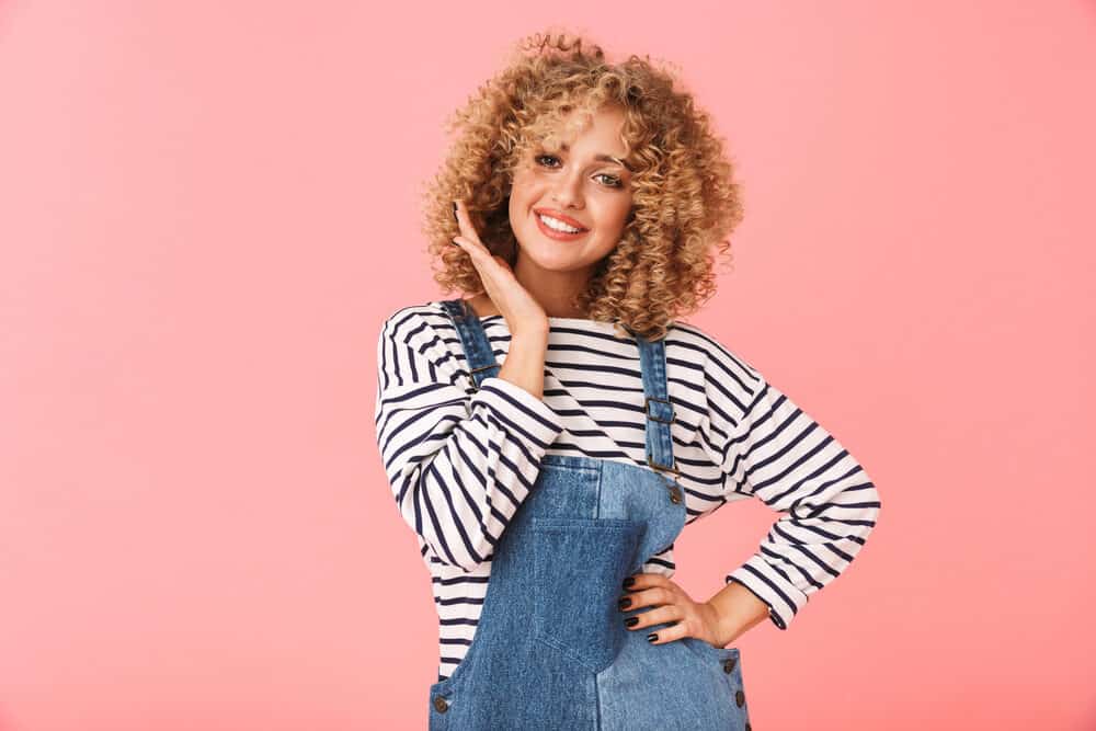 Pretty white female wearing blue jeans with natural curls with unique curl pattern on ombre hair strands