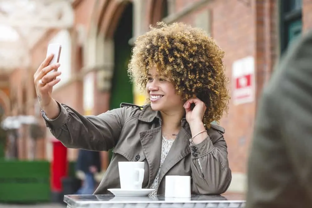 A woman taking a selfie with her smartphone at an outside café.