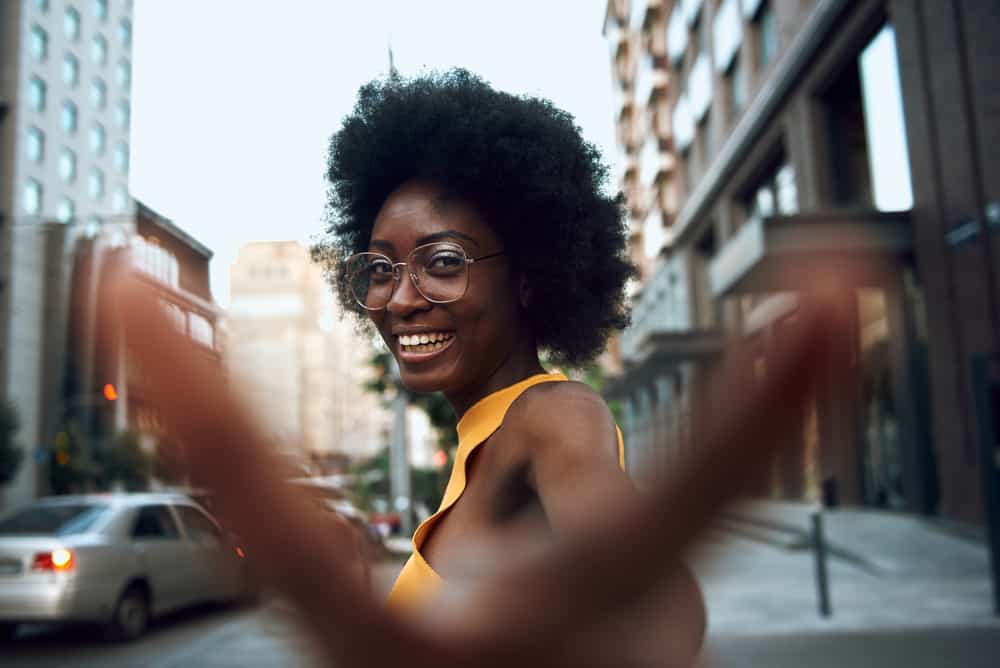 A beautiful woman in glasses strolling down the street and staring at the camera.