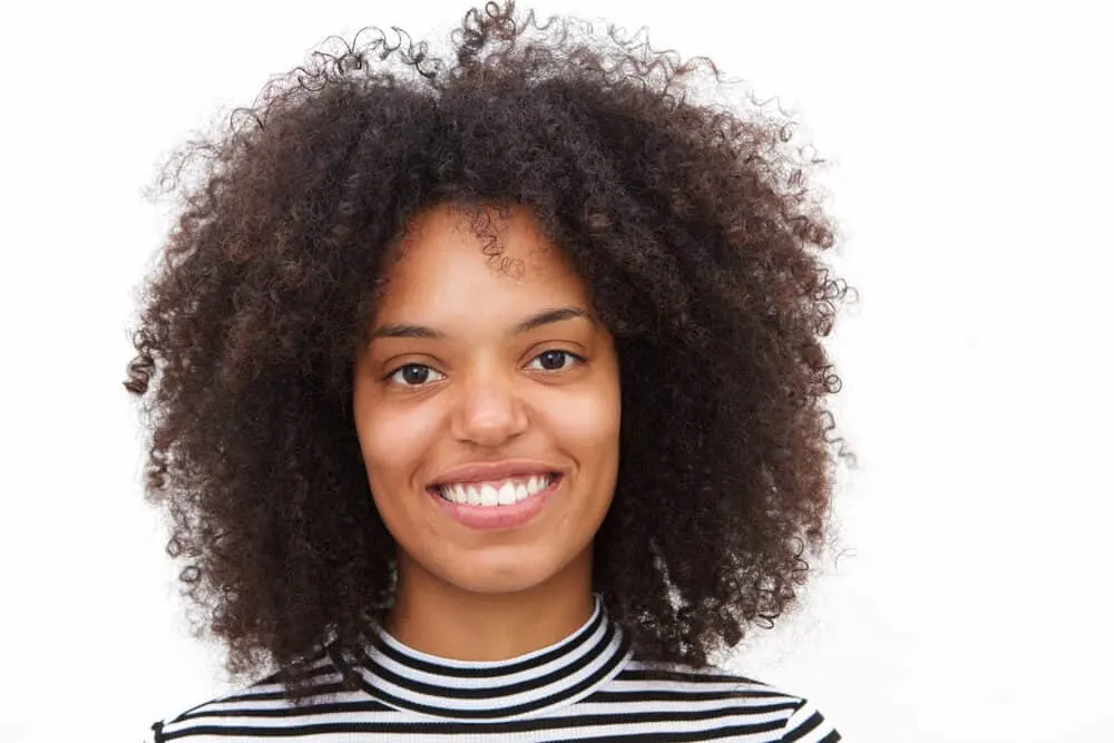 Rezo Cut: DIY Step-by-Step for Cutting Curly Hair at Home 1 Cute black female with a curly hair cut that focuses on her oval facial structure with long layers.