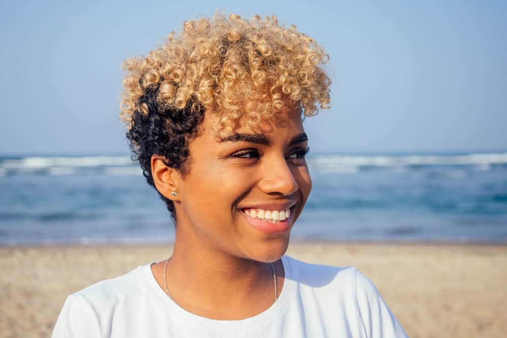 Afro-Latin lady with curly type 3C colored hair and perfect caramel skin enjoying a windy day at the beach