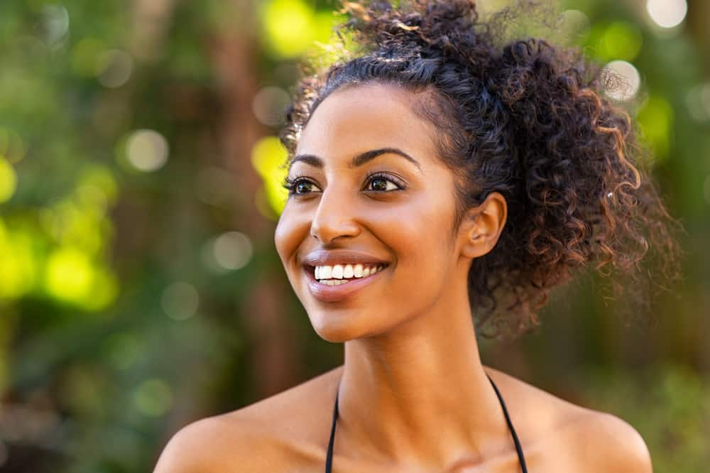 A young African-American woman with balayage curls styled with plastic-free, eco-friendly saponified oils.