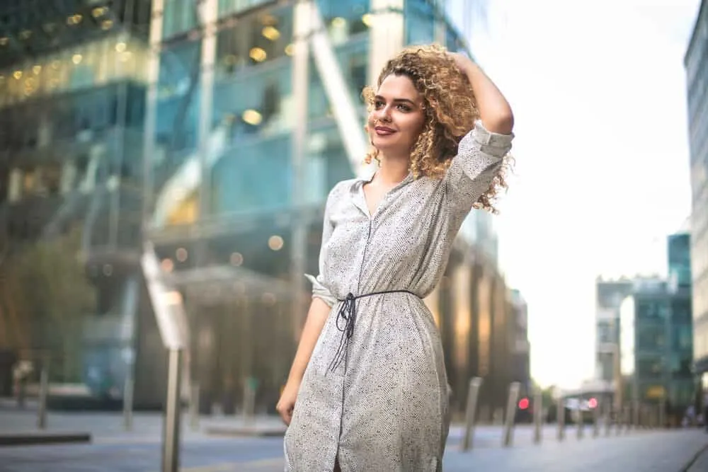 How To Get Rid of Brassy Hair at Home: DIY Step-by-Step Guide 4 Elegant woman walking down a busy sidewalk with red tones underlying warmth in wavy hair