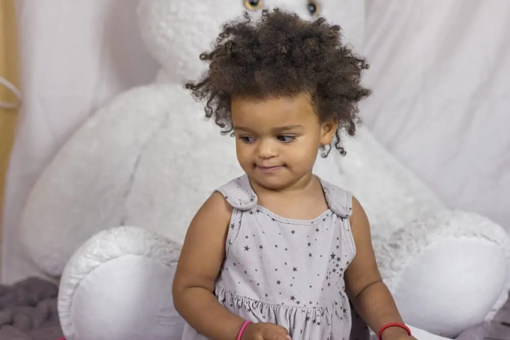 How To Get Slime Out Of Hair With Our Easy Step-by-Step Guide 2 Cute toddler girl with huge, brown eyes looking down playing with silly putty