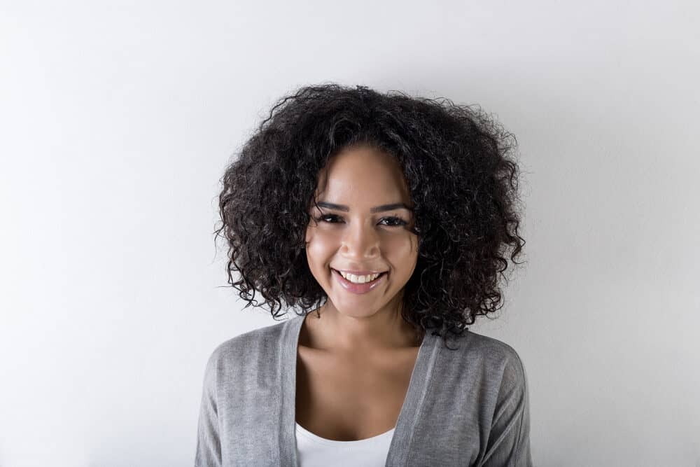 Pretty adult female wavy straight hair strands wearing a gray sweater and white t-shirt