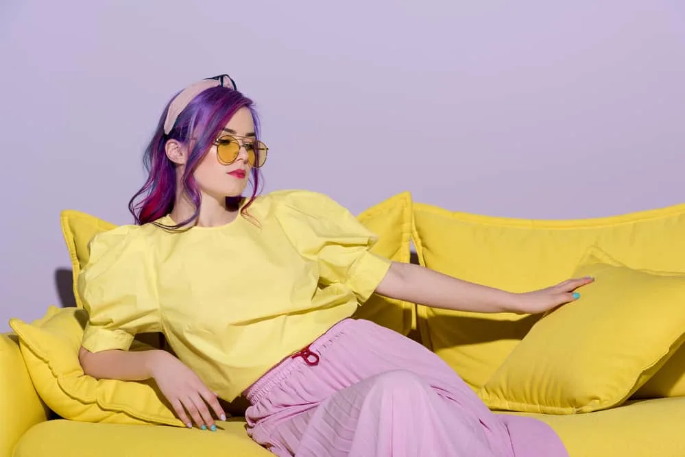 What Does Purple Hair Look Like When It Fades Over Time? 4 Caucasian women with faded Fuschia hair strands wearing a shirt with a bleach yellow tone and a pink ribbed skirt.