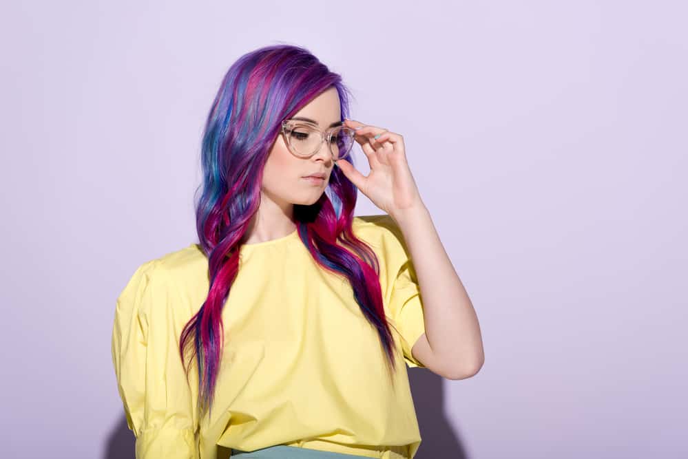 White girl with type 1 dark hair wearing clear glasses, a yellow shirt, and a blue skirt.