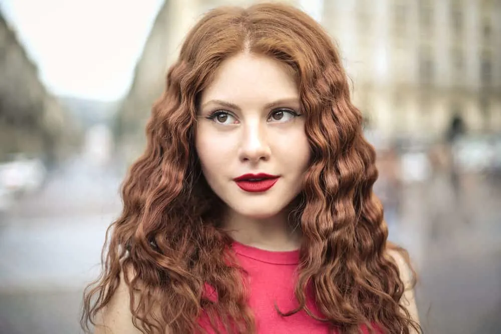 Cute female with a light perm and shoulder-length hair wearing red lipstick and neutral makeup.
