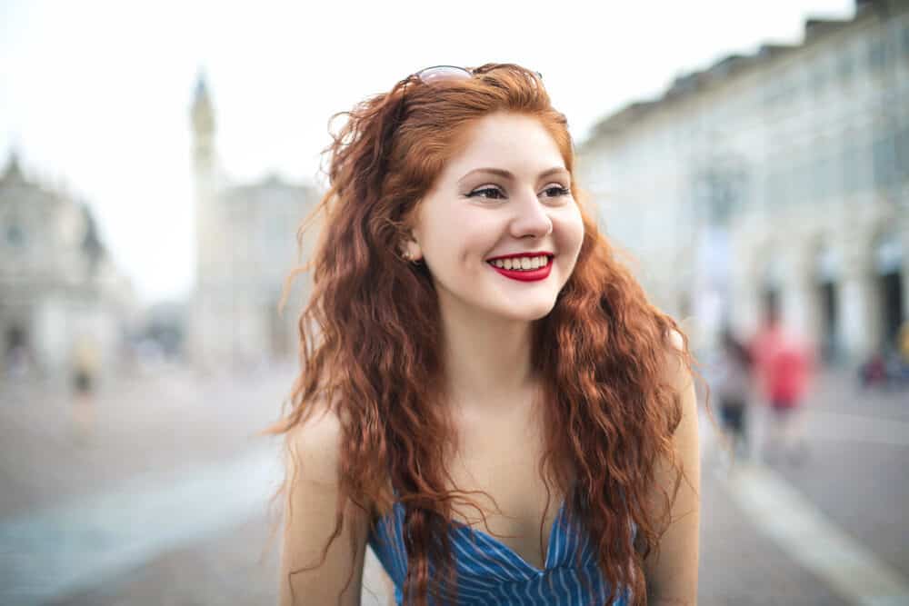 White woman with a body perm wearing a white and blue striped dress.