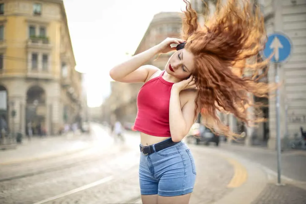 Woman dancing in the street with a tank top and blue jeans with a cute body perm.