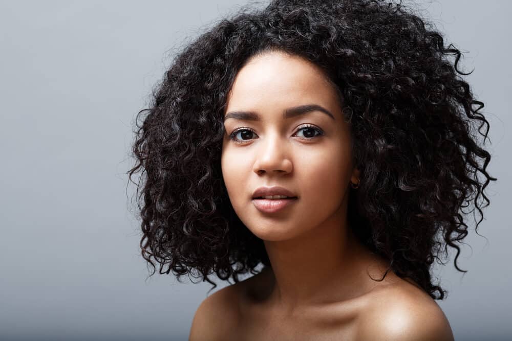 African American female with black wavy curly hair showing off her natural hair texture