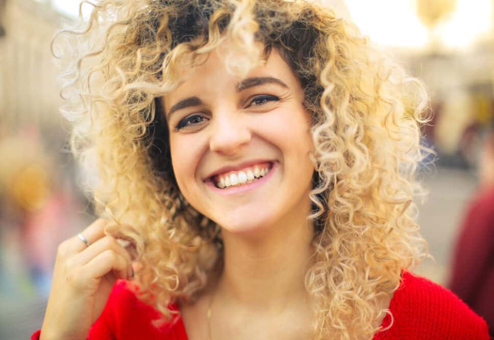 A lovely lady paying with her own hair while smiling.