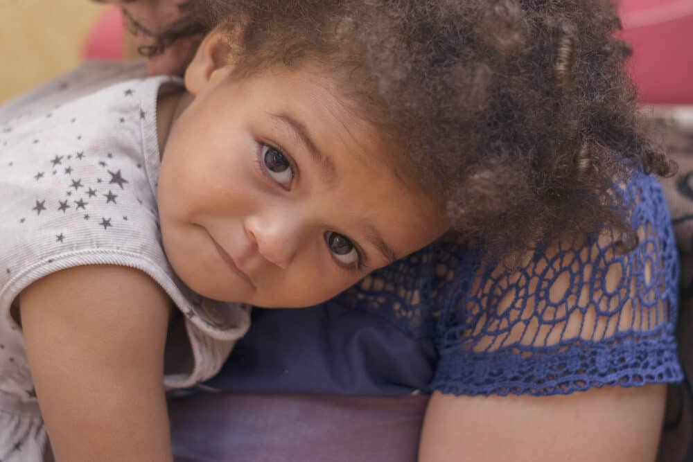 Cute African American girl laying on her mother's shoulder getting ready for a nap