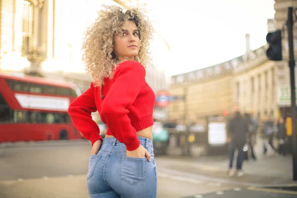  Jolie femme marchant dans la rue à Londres avec des boucles blondes teintées de shampooing violet.