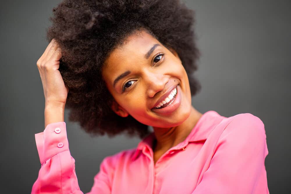 Black girl with natural hair wearing a pink shirt while showing off her hair following the maximum hydration method.