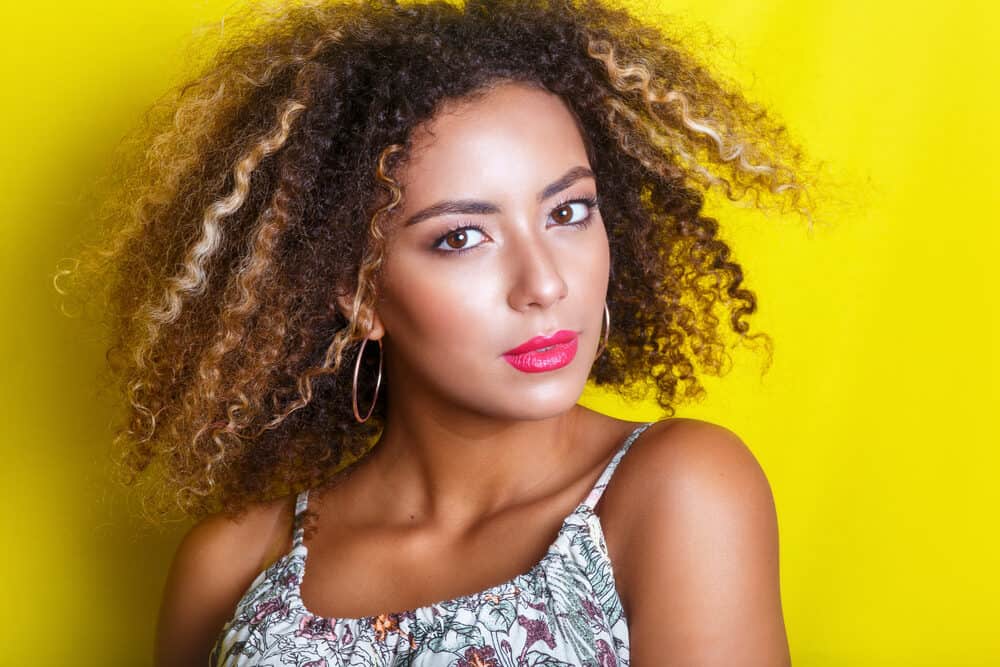 Cute mixed-raced female with wavy and curly hair with make-up and hoop earrings