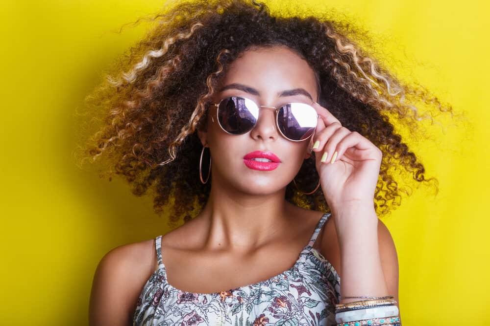 Fashionable African American lady wearing shades with a curly hair type