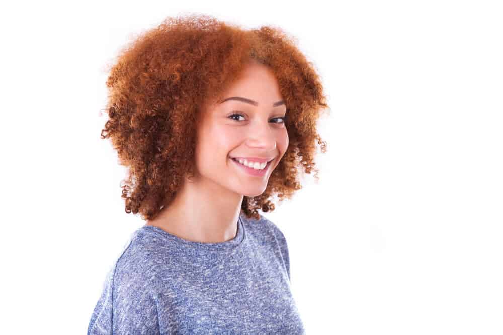Black girl with light skin and dark brown hair wearing a blue sweater