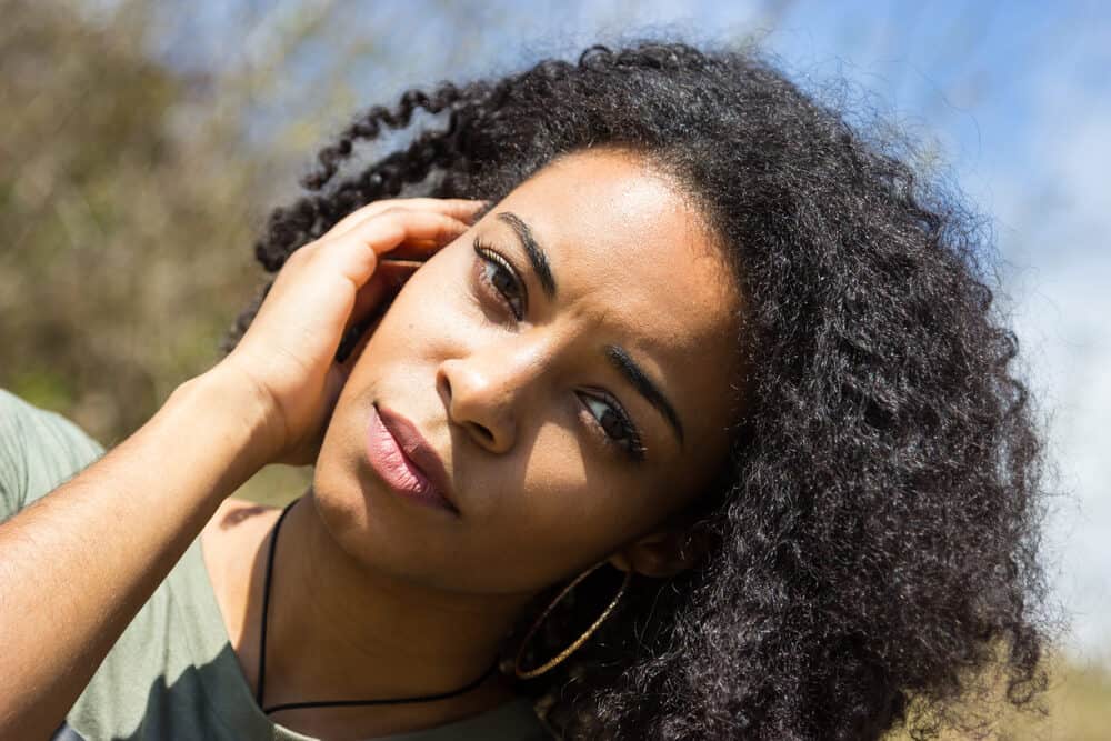 Cute female with naturally curly hair rubbing her fingers through her natural texture