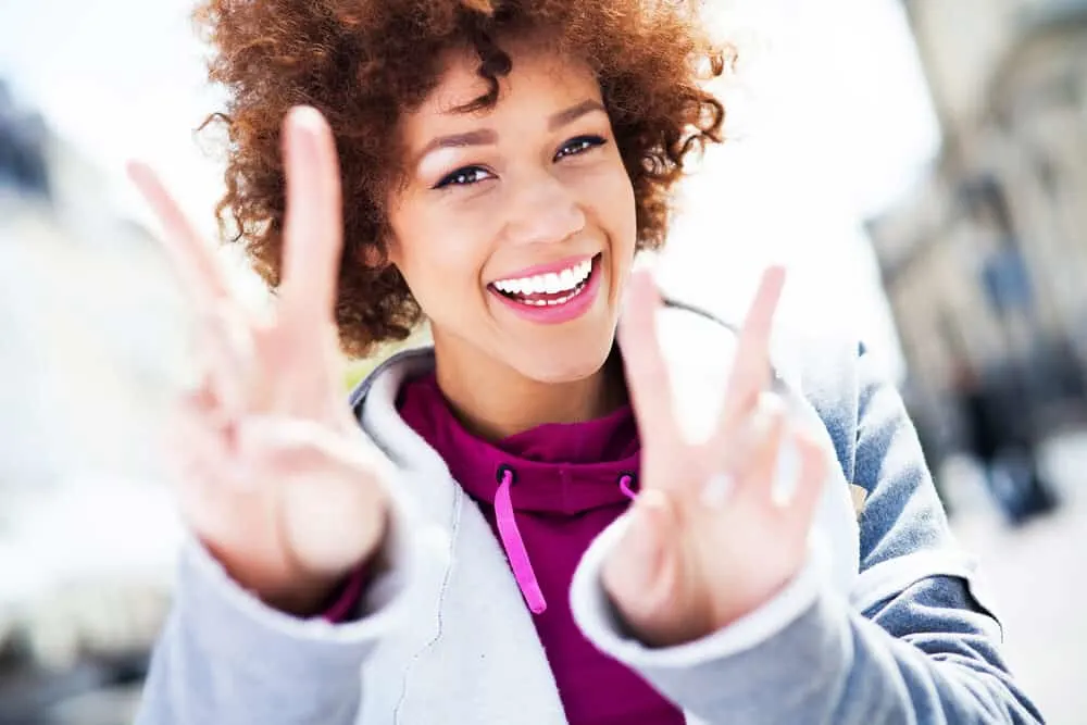 The Best Purple Hair Dye for Dark Hair Plus Alternatives 6 African American lady wearing a jogging suit with brown dyed hair