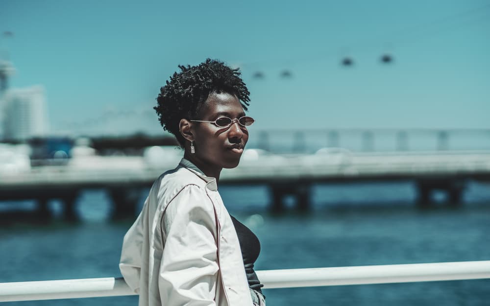 Lady standing outside at beach with a looser curl pattern starting thick locs