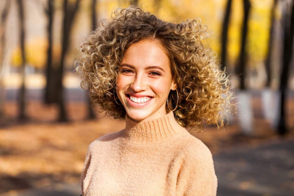 Young white girl wearing a beige sweater with permanent beach waves